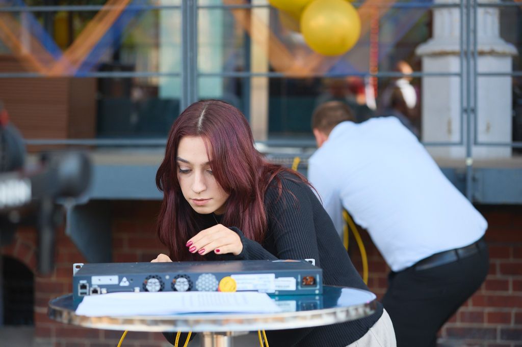 Auf dem Bild zu sehen: webgo Teammitglied Stefana beim konzentrierten verbinden des Servers. Im Hintergrund Gründer und Geschäftsführer Sebastian Angermeyer in Aktion.