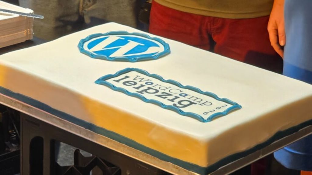 Torte mit WordPress-Logo und &bdquo;WordCamp Leipzig 2026&ldquo;-Schriftzug auf wei&szlig;em Fondant.