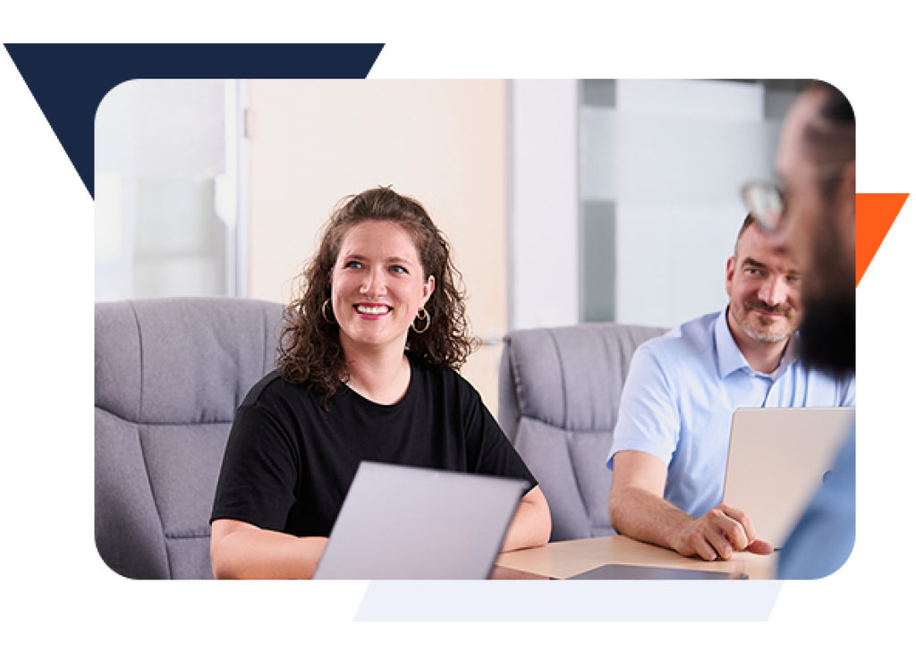 Drei webgo-Mitarbeitende in einem modernen B&uuml;ro im Gespr&auml;ch. Frau schaut l&auml;chelnd zur Seite.