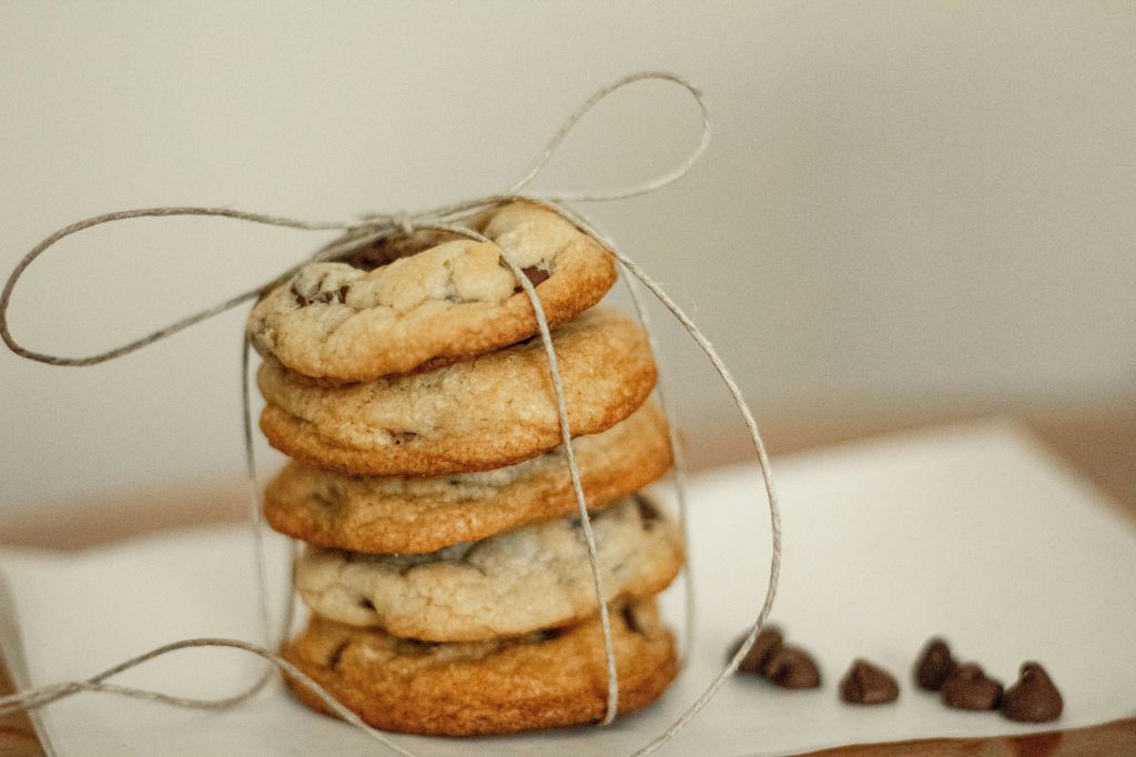Bild von fünf Cookies zusammen gebunden mit einem Paketband auf einer Serviette und einigen Schokodrops daneben.